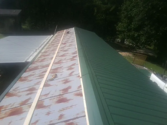 Old rusted panels beside newly installed green metal roofing — Wind Damage Roof Repair by Roofing Brothers in Allenport