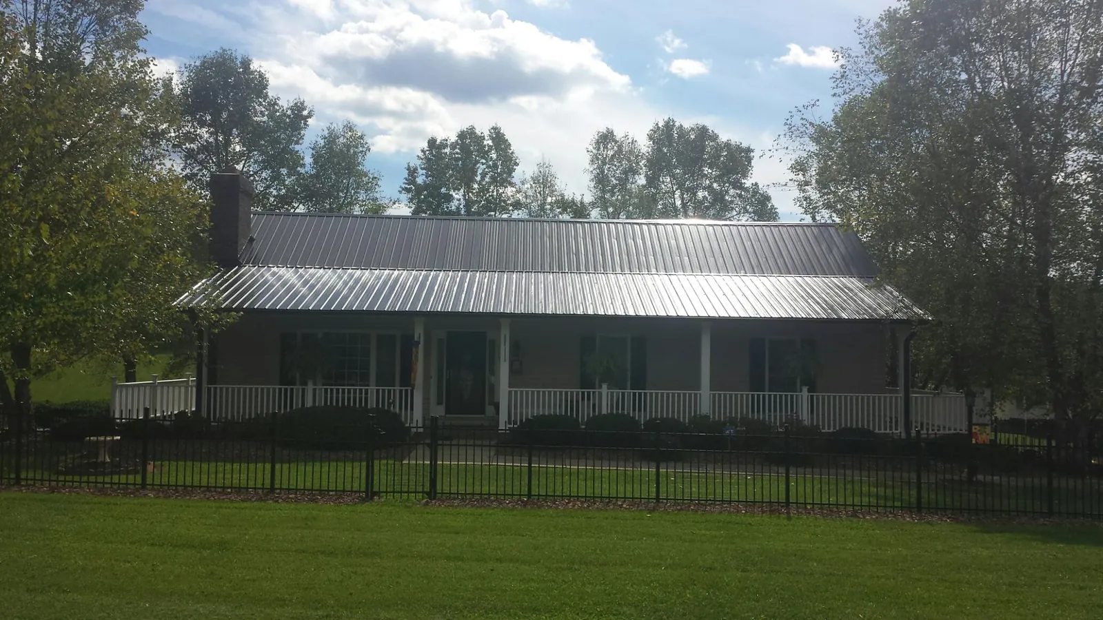 Gray metal roof on a brick ranch with a full width front porch — Gutter Guard Installation work by our crew in Allenport