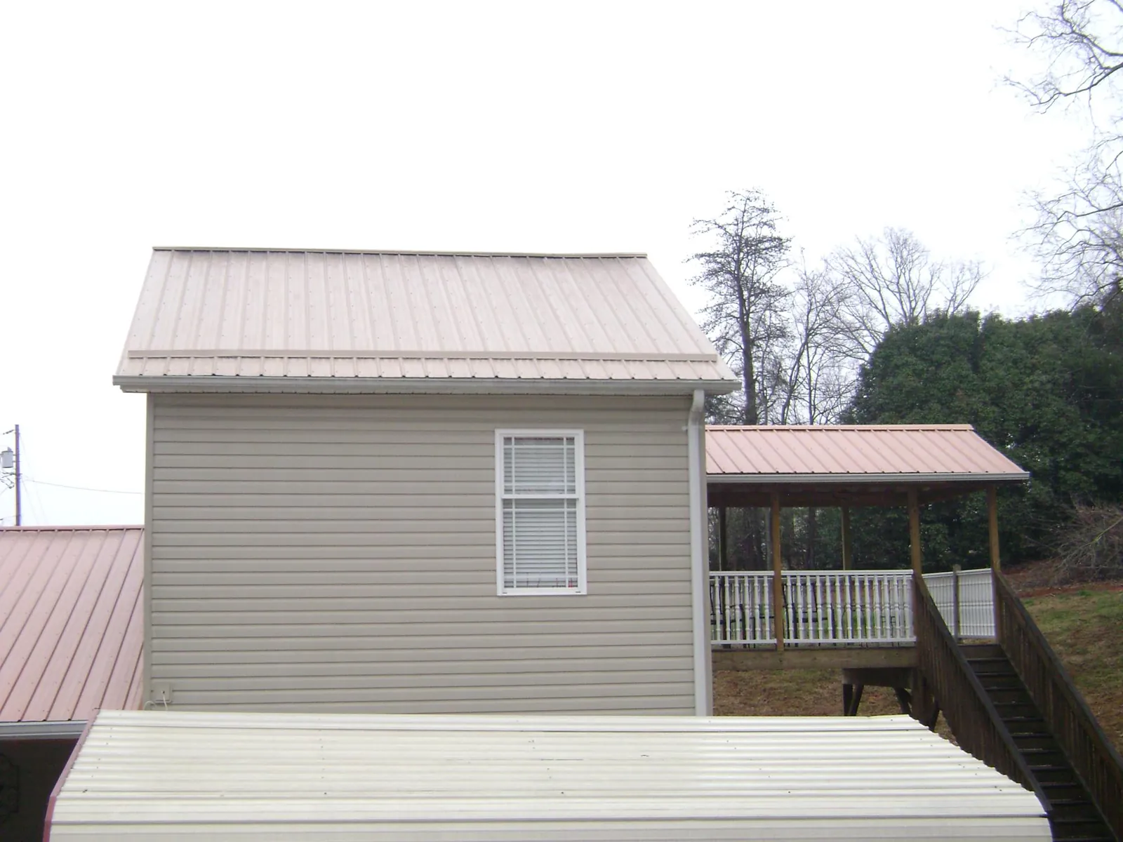Tan metal roofs on a two story addition and attached porch, from a Roof Replacement job in Allenport