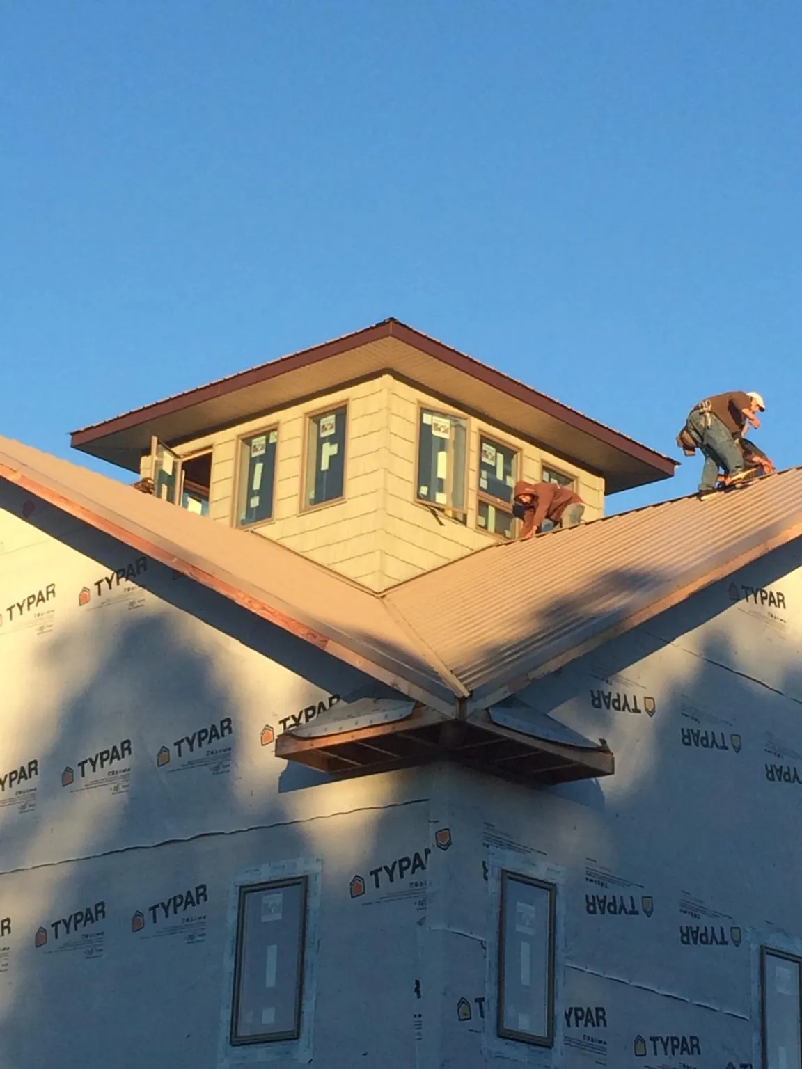 Roofers working around a rooftop cupola on a new metal roof at sunset — Roof Waterproofing in Allenport by Roofing Brothers